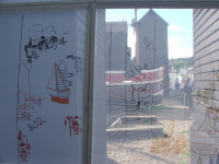 inside the drawing tent looking out through the screen and the drawings on it towards the Net Shops on the other side