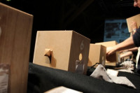 Line of spot-lit wooden boxes with peep holes